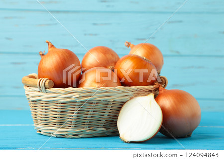 Fresh healthy onions and sliced onion on basket on blue wooden background. 124094843