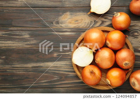 Fresh healthy onions and sliced onion on wooden board on brown wooden background. 124094857