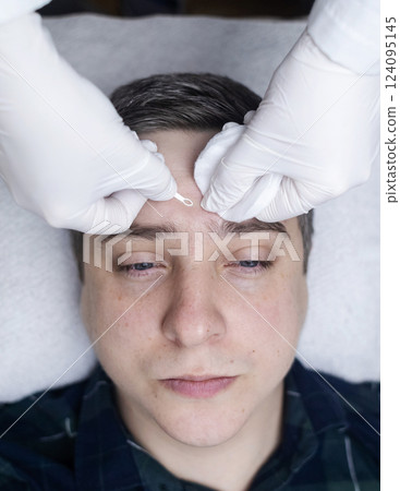 Man undergoing facial cleansing and blackhead removal. Beautician using comedone extractor or uno loop. Professional skin care in a beauty salon Man undergoing facial cleansing and blackhead removal. Beautician using comedone extractor or uno loop. Professional skin care in a beauty salon 124095145