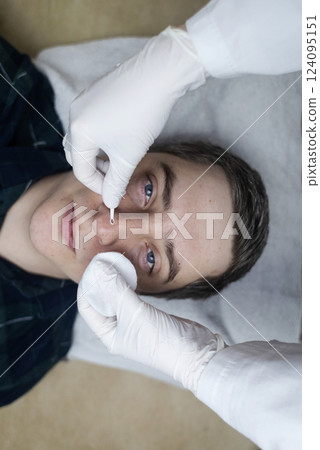 Man undergoing facial cleansing and blackhead removal. Beautician using comedone extractor or uno loop. Professional skin care in a beauty salon 124095151