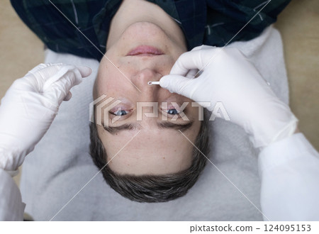 Man undergoing facial cleansing and blackhead removal. Beautician using comedone extractor or uno loop. Professional skin care in a beauty salon Man undergoing facial cleansing and blackhead removal. Beautician using comedone extractor or uno loop. Professional skin care in a beauty salon 124095153