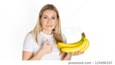 Young blonde beautiful woman holding banana. Blond woman in white t-shirt hold bananas on white background 124096107