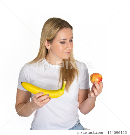Young blonde beautiful woman holding apple and banana. Blond woman in white t-shirt hold apple and banana on white background 124096123