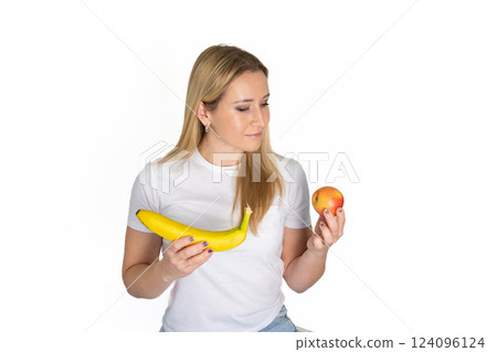 Young blonde beautiful woman holding apple and banana. Blond woman in white t-shirt hold apple and banana on white background 124096124