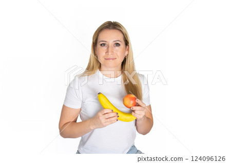 Young blonde beautiful woman holding apple and banana. Blond woman in white t-shirt hold apple and banana on white background Young blonde beautiful woman holding apple and banana. Blond woman in white t-shirt hold apple and banana on white background 124096126