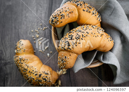 Bakery - various kinds of breadstuff. Bread rolls, bagel, sweet bun and croissant captured from above (top view, flat lay). Grey rustic wooden background. 124096397