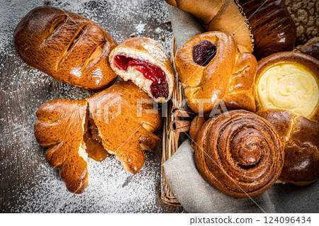 Bakery - various kinds of breadstuff. Bread rolls, baguette, bagel, sweet bun and croissant captured from above (top view, flat lay). wooden rustic background, copy space. Horizontal banner layout. Bakery - various kinds of breadstuff. Bread rolls, baguette, bagel, sweet bun and croissant captured from above (top view, flat lay). wooden rustic background, copy space. Horizontal banner layout. 124096434