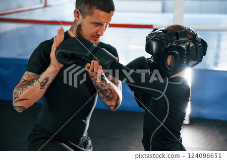 Doing some punches. Coach is teaching the boy box techniques indoors 124096651