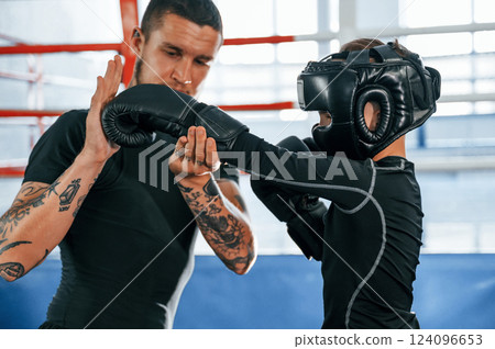 Practicing the punches. Coach is teaching the boy box techniques indoors Practicing the punches. Coach is teaching the boy box techniques indoors 124096653