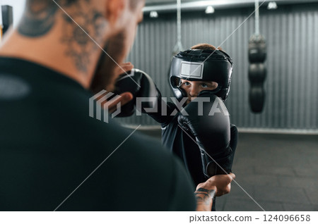 Practicing the punches. Coach is teaching the boy box techniques indoors Practicing the punches. Coach is teaching the boy box techniques indoors 124096658
