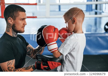 Side view. Coach is teaching the boy box techniques indoors 124096679
