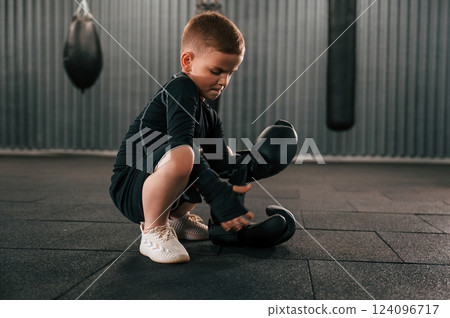 Wearing the glowes. Boy is practicing boxing in the gym 124096717