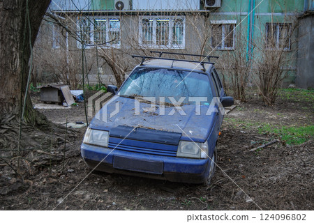 A dirty car from the Ukrainian auto industry. A dirty, abandoned blue car covered in leaves is a depressingly sad sight. A dirty car from the Ukrainian auto industry. A dirty, abandoned blue car covered in leaves is a depressingly sad sight. 124096802
