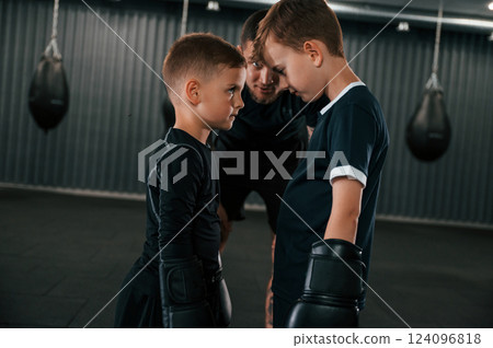 Preparing for the sparring. Young tattooed coach teaching the kids boxing techniques 124096818