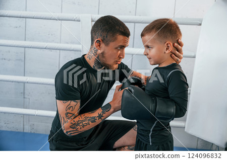 Together on the ring. Coach is teaching the boy box techniques indoors Together on the ring. Coach is teaching the boy box techniques indoors 124096832