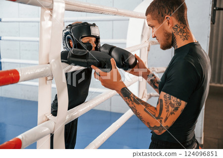 In protective helmet and with glowes. On the ring. Coach is teaching the boy box techniques indoors 124096851