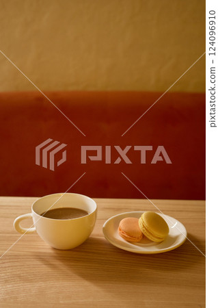 A warm cup of coffee sits beside a plate of colorful macarons on a wooden table in a peaceful cafe setting during the afternoon, creating a perfect moment for relaxation A warm cup of coffee sits beside a plate of colorful macarons on a wooden table in a peaceful cafe setting during the afternoon, creating a perfect moment for relaxation 124096910
