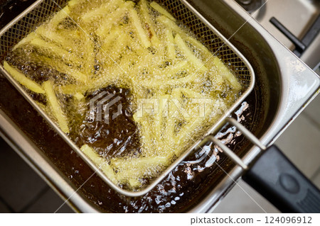 Freshly cut potato strips sizzle in bubbling oil, transforming into crispy golden fries. The bustling kitchen emits delicious aromas as they cook to perfection Freshly cut potato strips sizzle in bubbling oil, transforming into crispy golden fries. The bustling kitchen emits delicious aromas as they cook to perfection 124096912