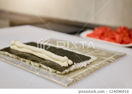 Fresh sushi ingredients are neatly arranged on a sushi mat, showcasing the art of preparation. Rice and seaweed are ready for rolling, indicating craftsmanship and culinary skill Fresh sushi ingredients are neatly arranged on a sushi mat, showcasing the art of preparation. Rice and seaweed are ready for rolling, indicating craftsmanship and culinary skill 124096916