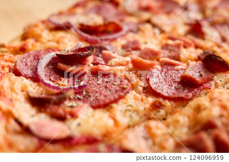 Freshly baked pizza is topped with savory pepperoni, sausage, and sliced onions, showcasing a crispy crust and melted cheese. Perfect for a casual meal at home Freshly baked pizza is topped with savory pepperoni, sausage, and sliced onions, showcasing a crispy crust and melted cheese. Perfect for a casual meal at home 124096959
