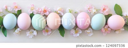 Colorful Easter eggs in pastel shades are nestled among delicate spring flowers on a rustic wooden surface 124097336