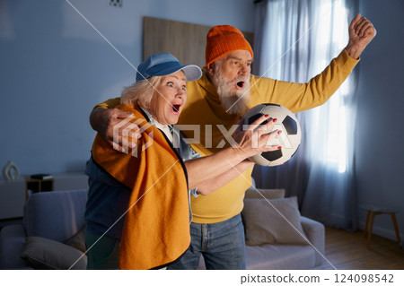Overjoyed elderly couple watching football match on tv 124098542