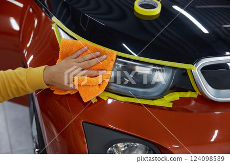 Man technician rubbing surface headlamps with microfiber cloth closeup 124098589