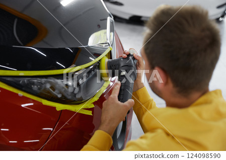 Service technician polishing headlamps at car garage workshop 124098590