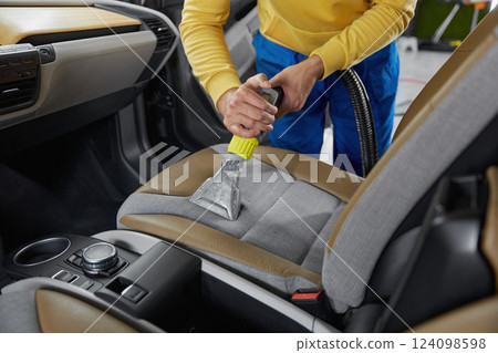 Man car wash service worker vacuuming dust form seats 124098598
