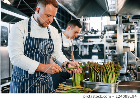 Many of the asparagus raw products. Kitchen workers is together preparing the food 124099194