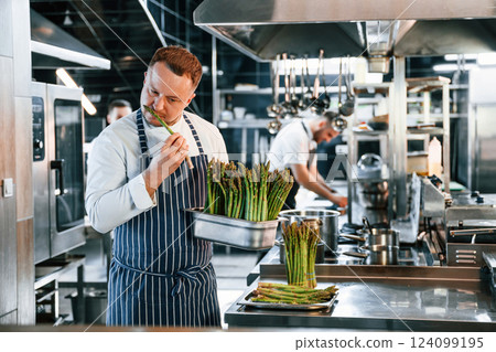 Many of the asparagus raw products. Kitchen workers is together preparing the food 124099195