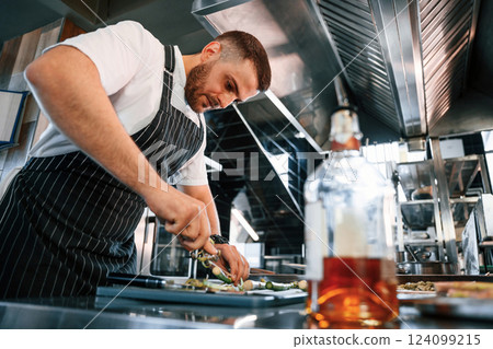 Slicing and cutting asparagus. Chef is on the kitchen preparing food Slicing and cutting asparagus. Chef is on the kitchen preparing food 124099215