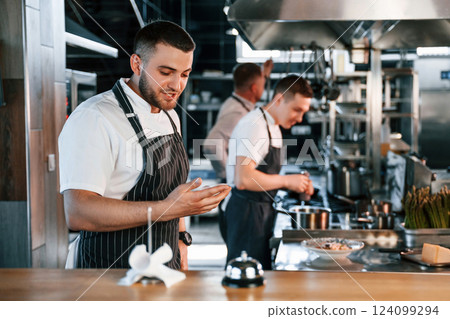 Standing near the table with bell. Kitchen workers is together preparing the food 124099294