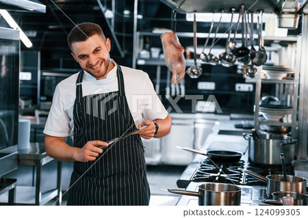 Standing and looking at the camera. Chef is on the kitchen preparing food Standing and looking at the camera. Chef is on the kitchen preparing food 124099305