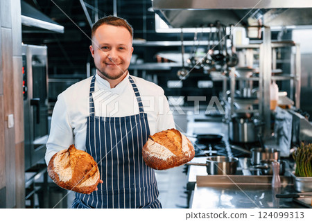 Holding fresh bread. Chef is on the kitchen preparing food 124099313