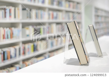 Bookstore with with blurred shelves and books on table, soft focus. Books displayed on acrylic stands in modern library . Education, school, study, reading fiction concept. For background, copy space 124099913