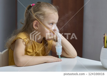 A bored and coughing sick girl is treated with a nebulizer A bored and coughing sick girl is treated with a nebulizer 124100016