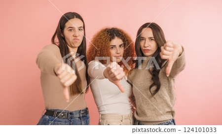Three women expressing disapproval with thumbs down Three women expressing disapproval with thumbs down 124101033