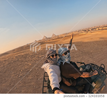 Tourists riding quad bike near giza pyramids at sunset, egypt Tourists riding quad bike near giza pyramids at sunset, egypt 124101058