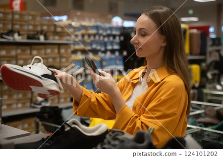 Woman scans shoes while shopping in a retail store for styles and sizes during a weekend visit Woman scans shoes while shopping in a retail store for styles and sizes during a weekend visit 124101202