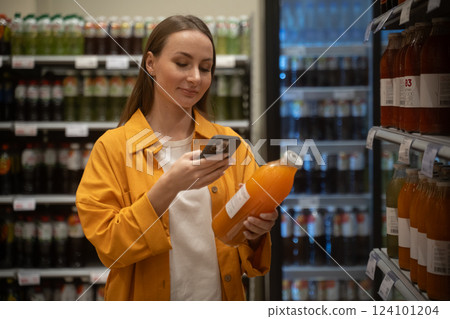 Woman scans orange juice while shopping in store and enjoying a grocery run 124101204