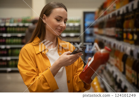 Woman scans tomato juice in grocery store aisle during afternoon shopping 124101249