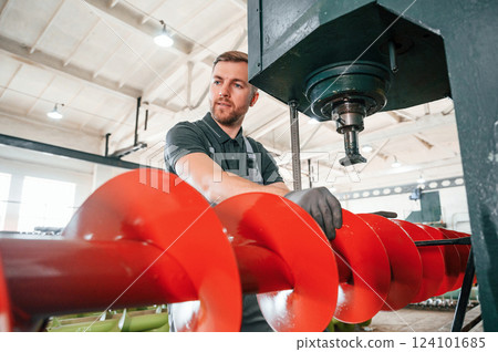 Attention to detail. Man in uniform is in workstation developing parts of agriculture technique Attention to detail. Man in uniform is in workstation developing parts of agriculture technique 124101685