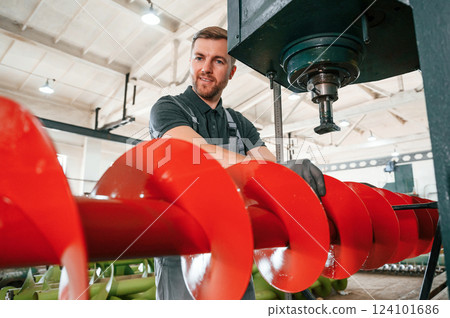 Attention to detail. Man in uniform is in workstation developing parts of agriculture technique Attention to detail. Man in uniform is in workstation developing parts of agriculture technique 124101686