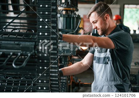 Metal processing device. Man in uniform is in workstation developing details of agriculture technique Metal processing device. Man in uniform is in workstation developing details of agriculture technique 124101706