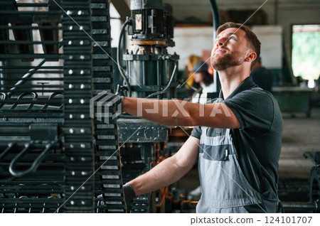 Metal processing device. Man in uniform is in workstation developing details of agriculture technique Metal processing device. Man in uniform is in workstation developing details of agriculture technique 124101707