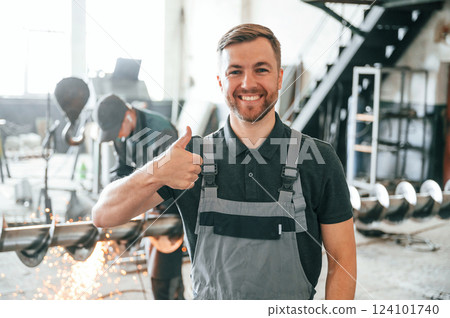 Standing and smiling. Man in uniform is in workstation developing details of agriculture technique Standing and smiling. Man in uniform is in workstation developing details of agriculture technique 124101740
