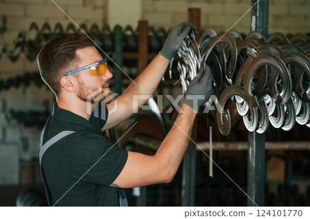 In protective glasses. Man in uniform is in workstation developing details of agriculture technique In protective glasses. Man in uniform is in workstation developing details of agriculture technique 124101770