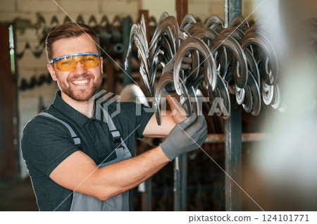 In protective glasses. Man in uniform is in workstation developing details of agriculture technique In protective glasses. Man in uniform is in workstation developing details of agriculture technique 124101771