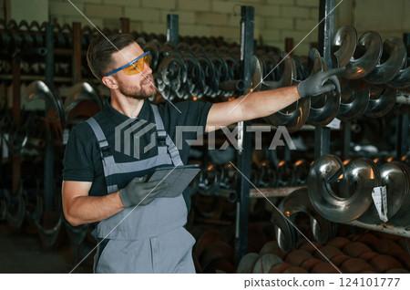 Standing with tablet. Man in uniform is in workstation developing details of agriculture technique Standing with tablet. Man in uniform is in workstation developing details of agriculture technique 124101777